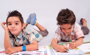 jumeaux allongés sur le sol pour faire leurs devoirs